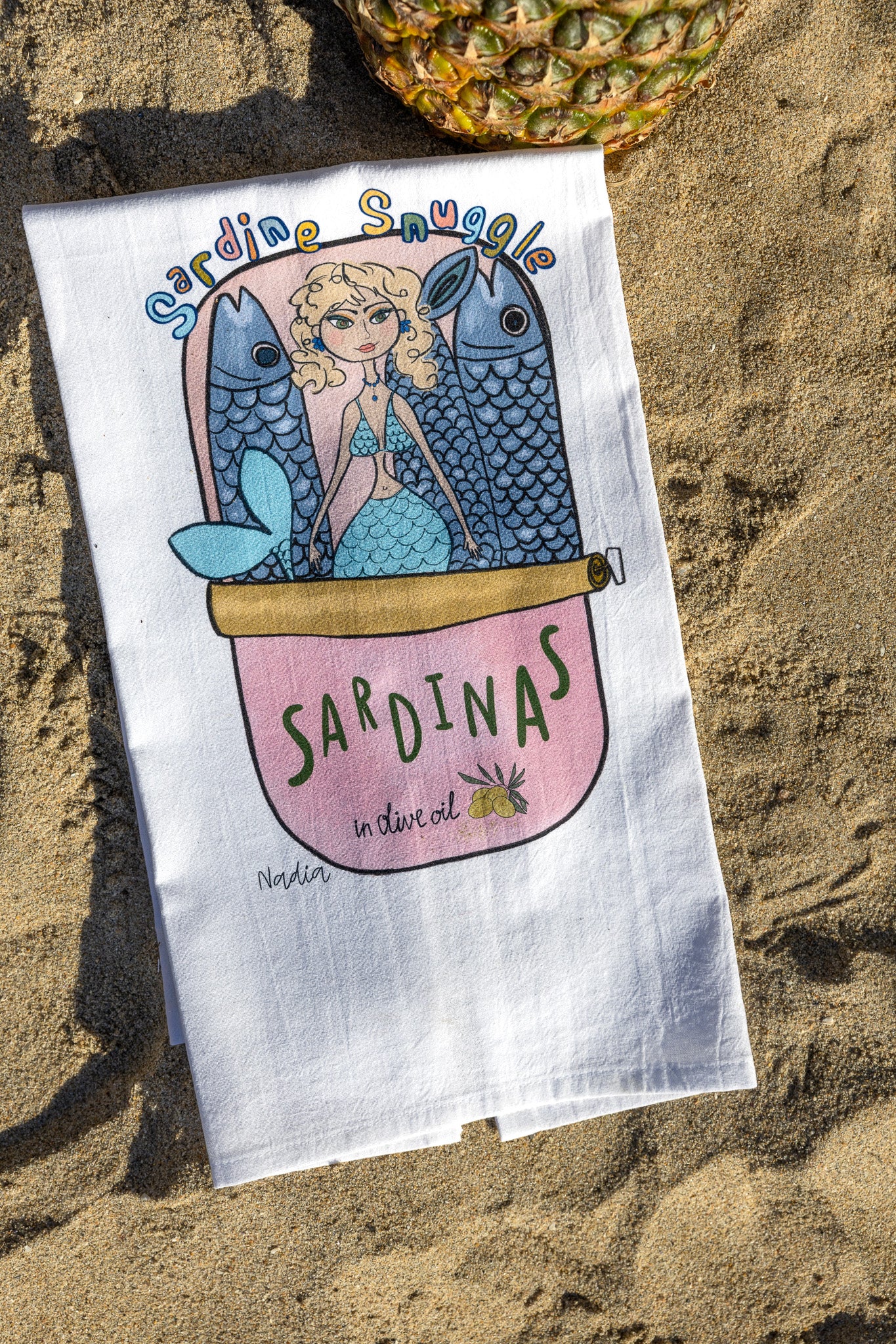 18x28 inch white thin cotton kitchen towel with a mermaid in a pink sardine tin illustration signed by Nadia Watts