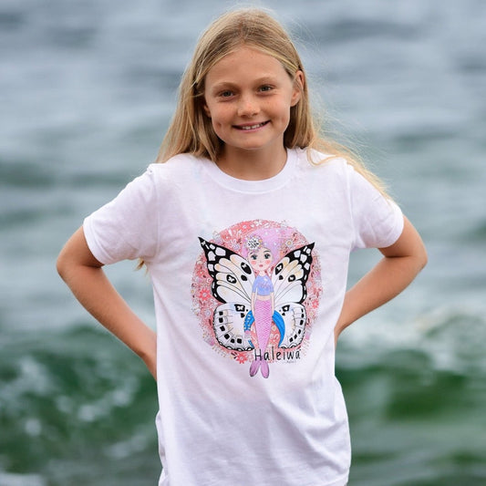 Girl's graphic tee featuring mermaid with butterfly wings, surrounded by colorful Hawaiian florals.