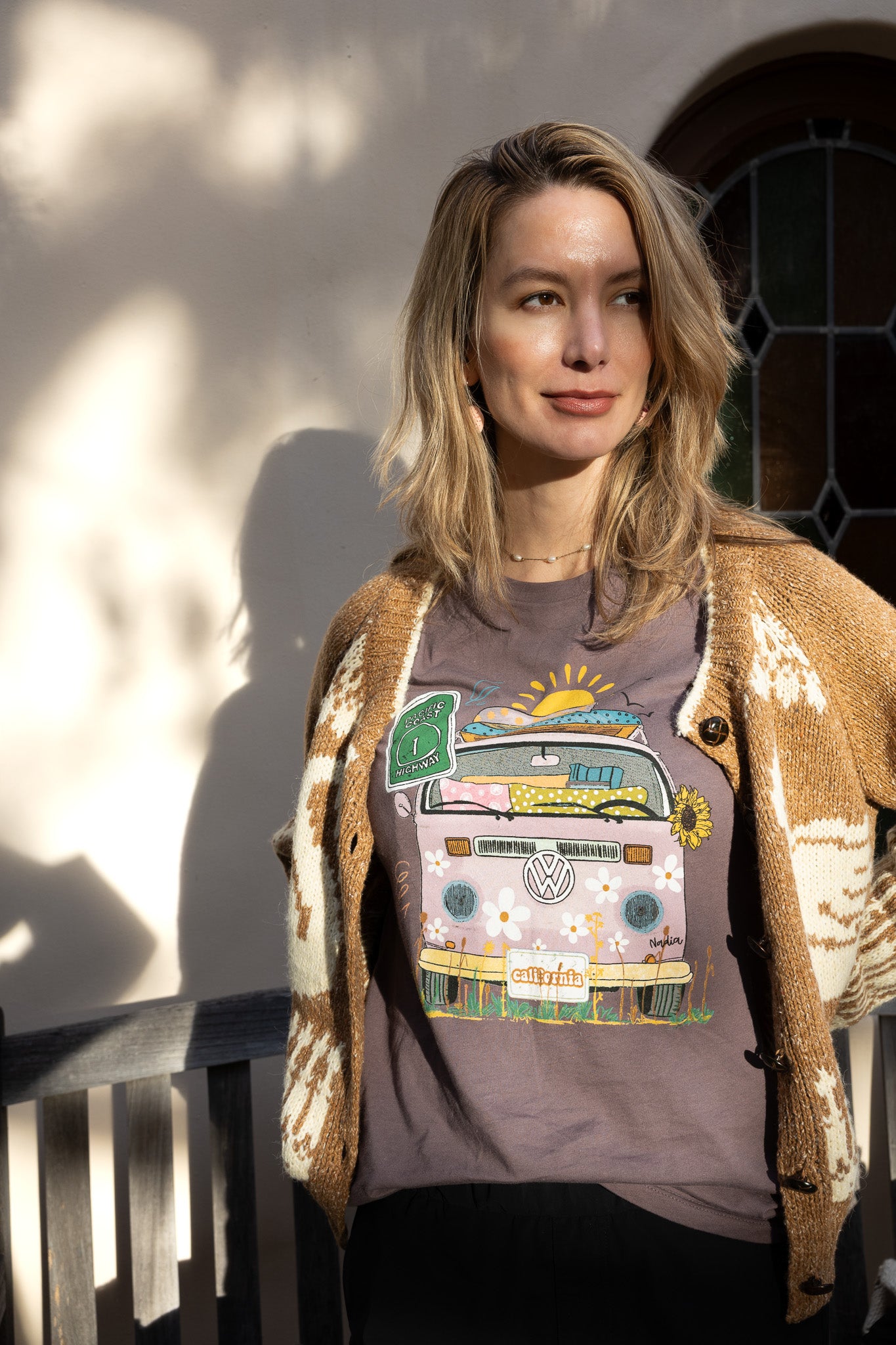 Woman in a purple North Shore Girls graphic t-shirt features a hand-drawn vintage floral beach van.