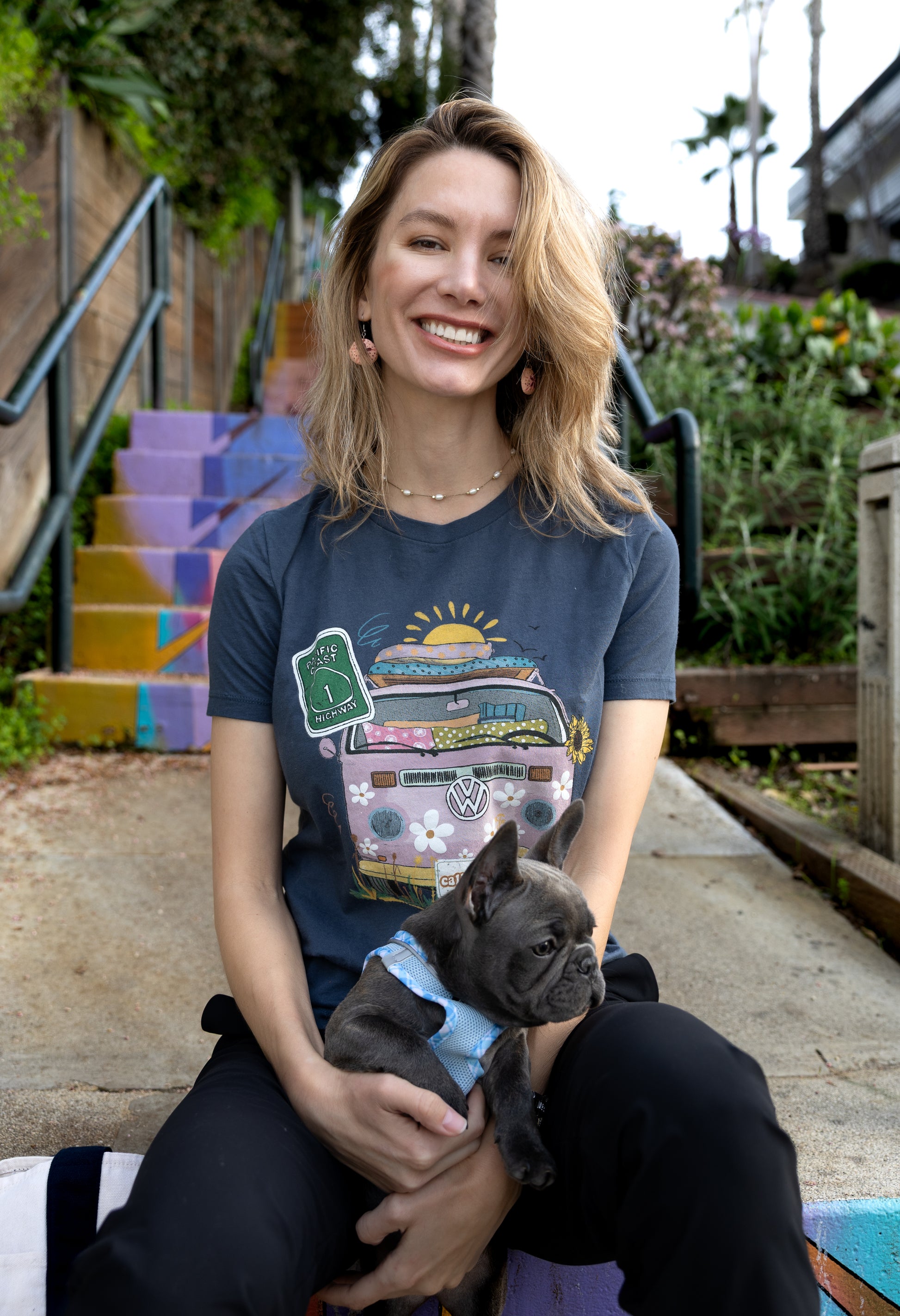Woman in a blue North Shore Girls graphic t-shirt features a hand-drawn vintage floral beach van.