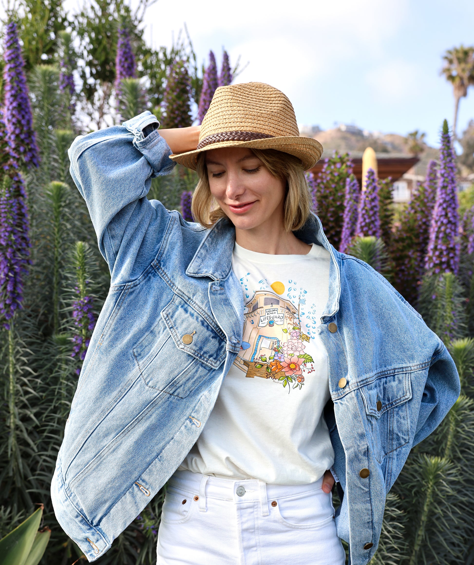 Nadia Watts -artist and graphic designer wearing her graphic tee featuring  an illustration of Laguna Beach Lifeguard Tower