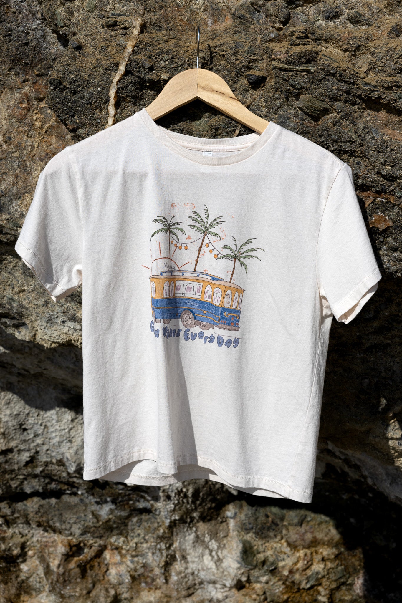 Illustration of Laguna Beach Transit and palm trees on a soft cotton tee, signed by artist Nadia Watts.