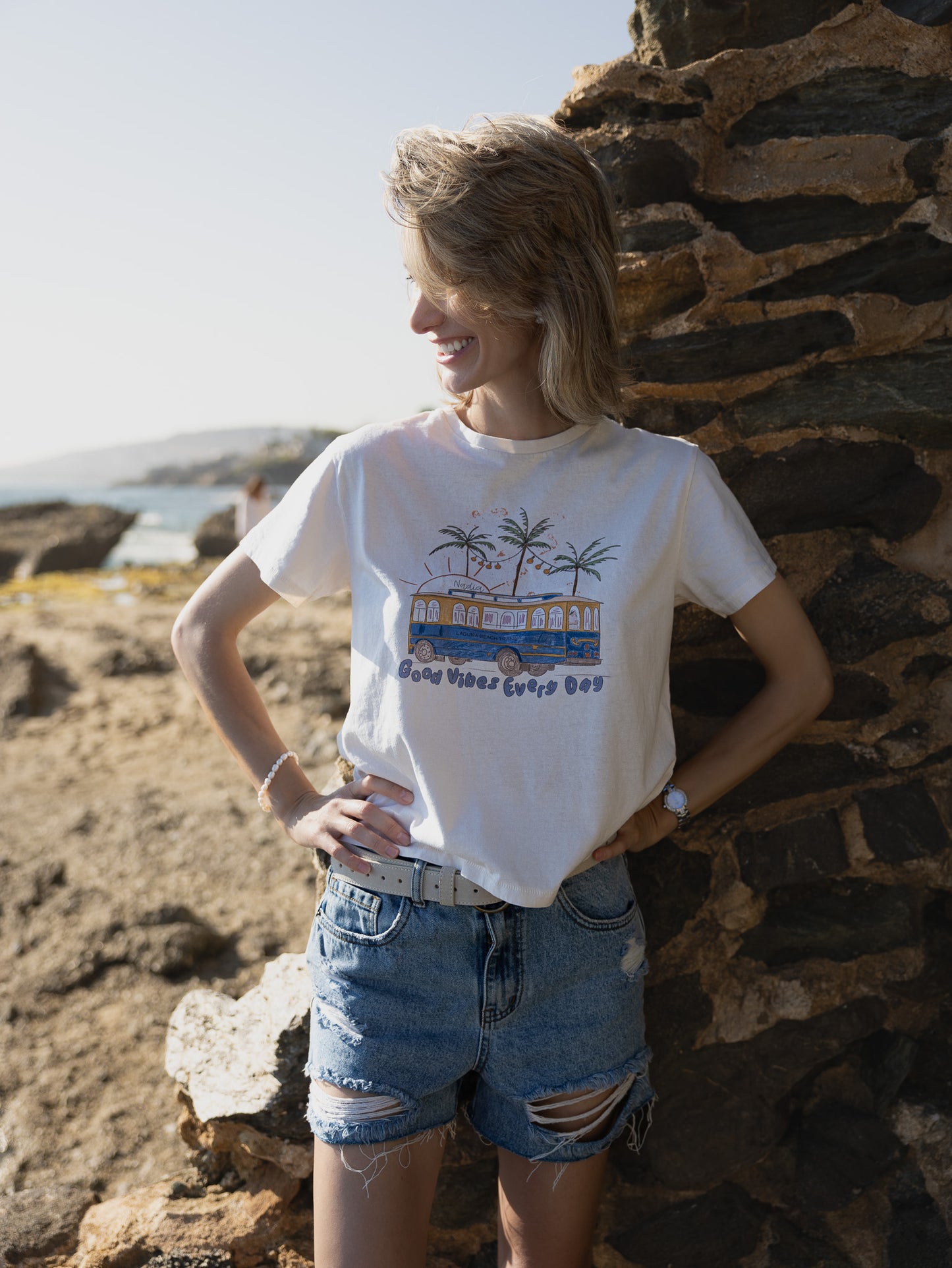 Illustration of Laguna Beach Transit and palm trees on a soft cotton tee, signed by artist Nadia Watts.