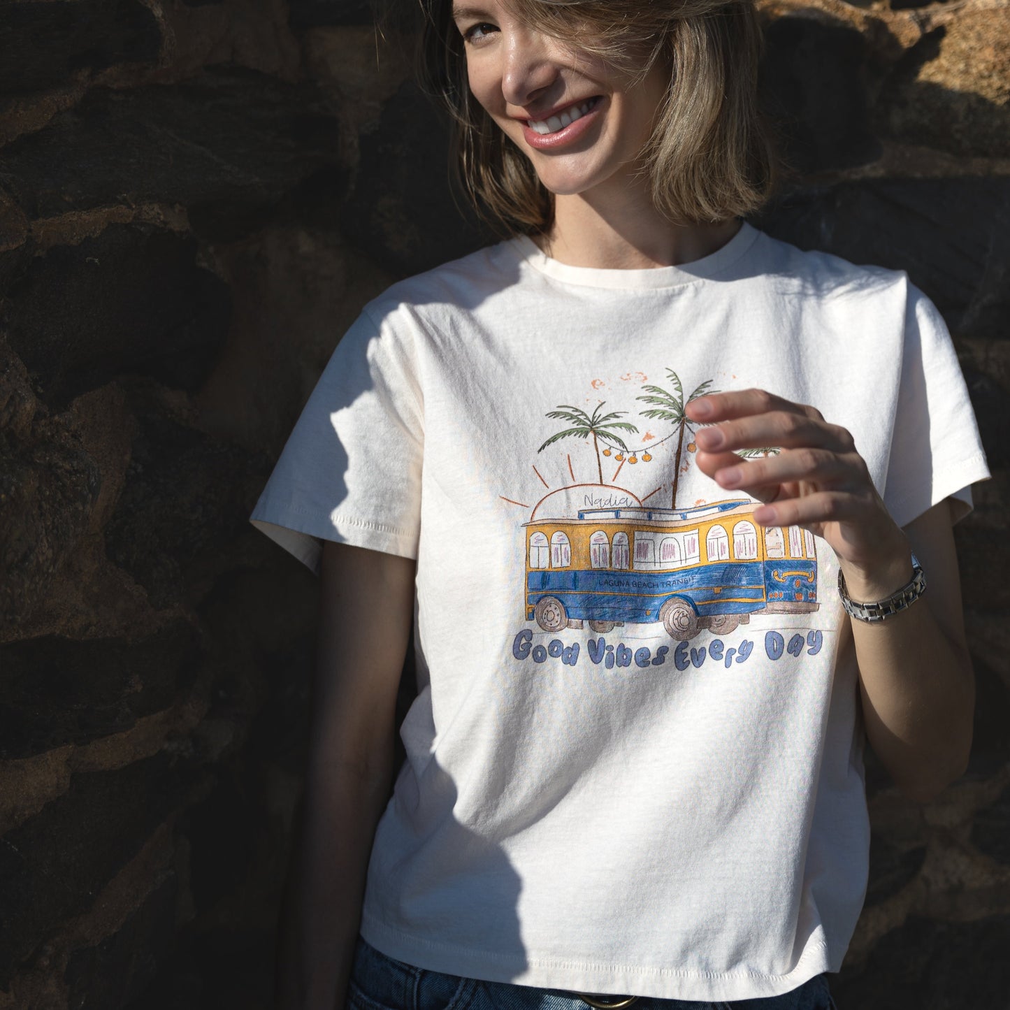 Illustration of Laguna Beach Transit and palm trees on a soft cotton tee, signed by artist Nadia Watts.