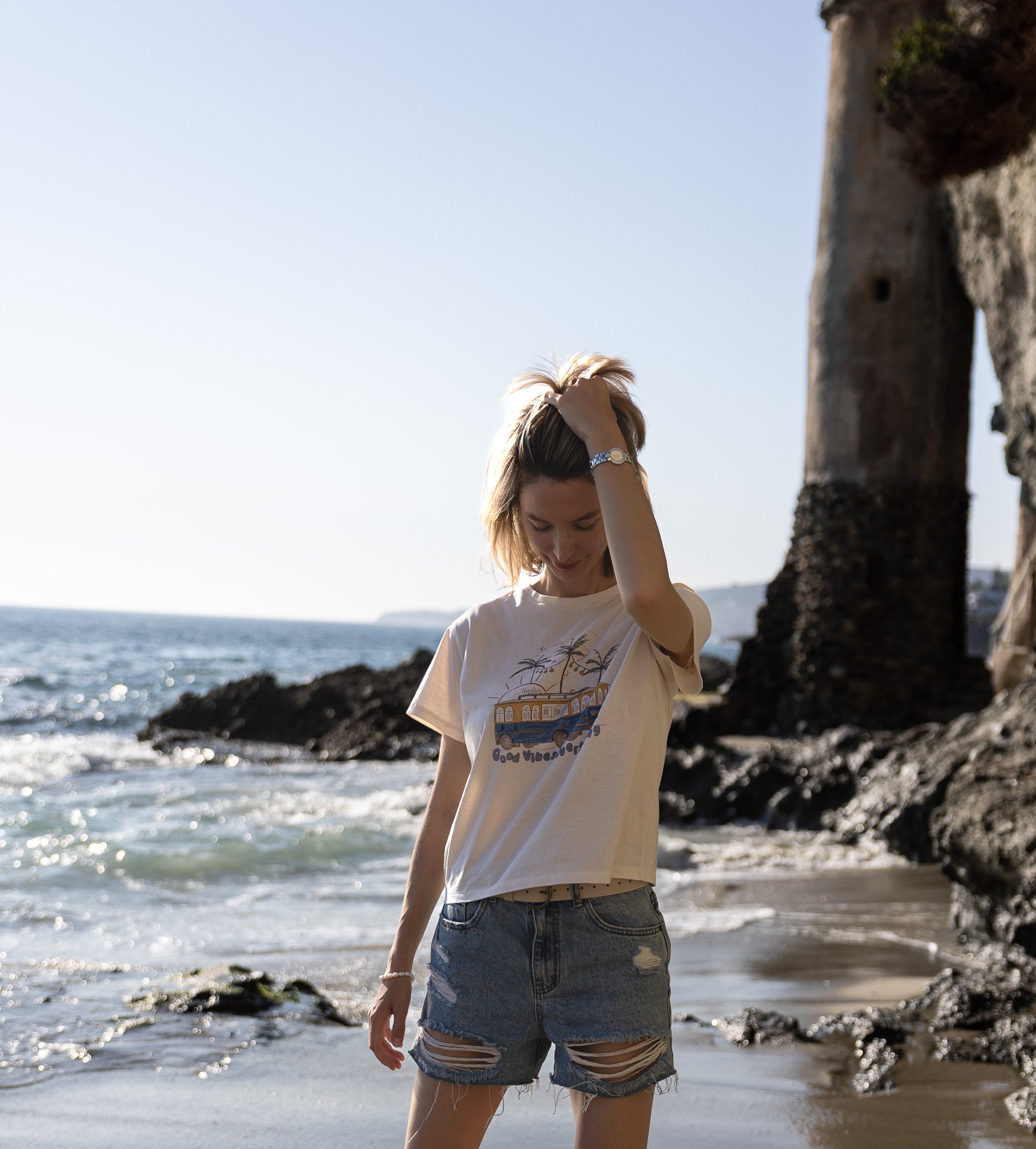 Illustration of Laguna Beach Transit and palm trees on a soft cotton tee, signed by artist Nadia Watts.