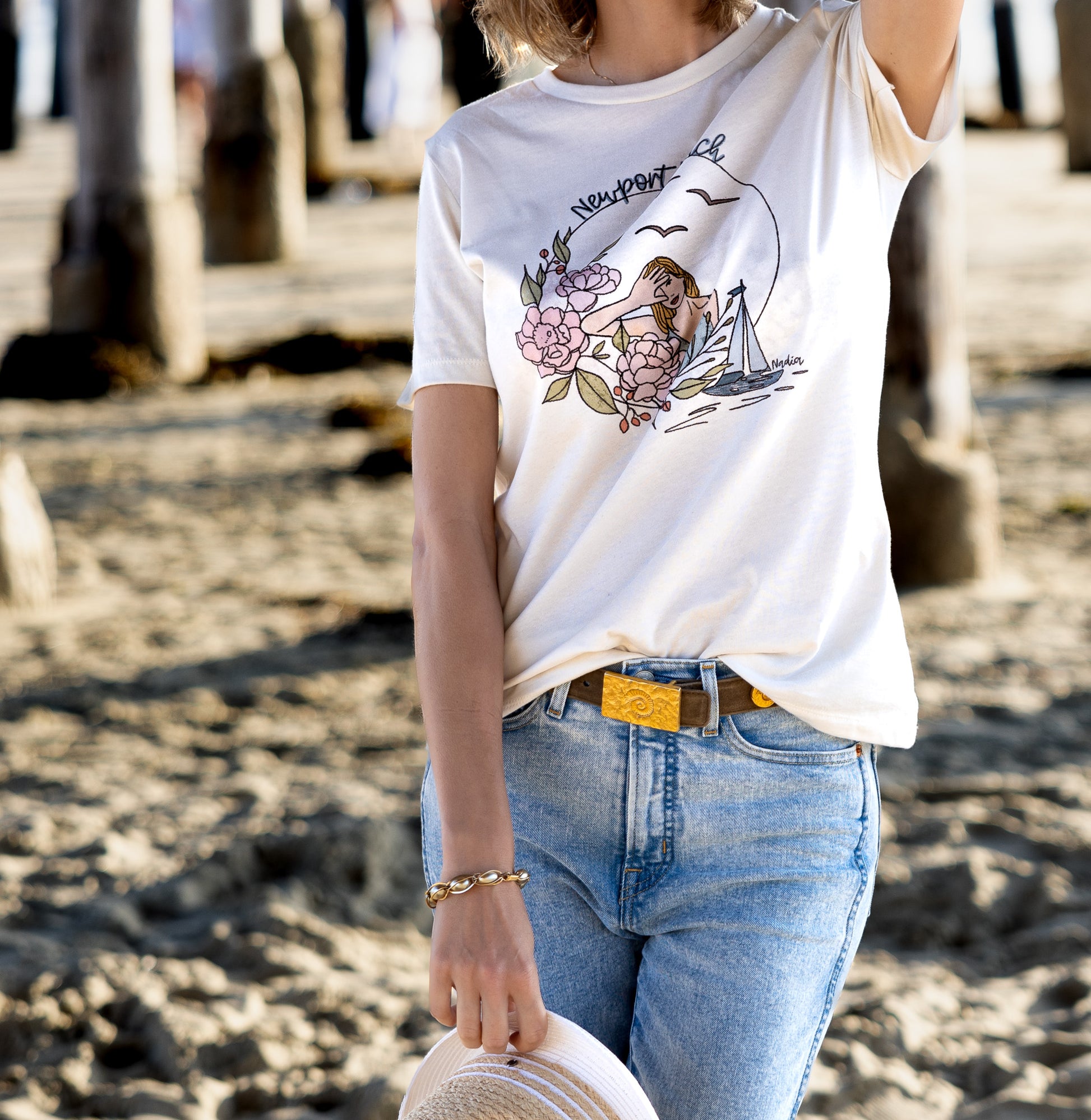 Newport Beach graphic tee featuring illustrated woman, flowers, boat and signed by the artist Nadia Watts