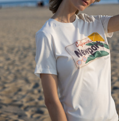 Woman is wearing North Shore Girls tee with a Newport California license plate illustration and palm leaves.