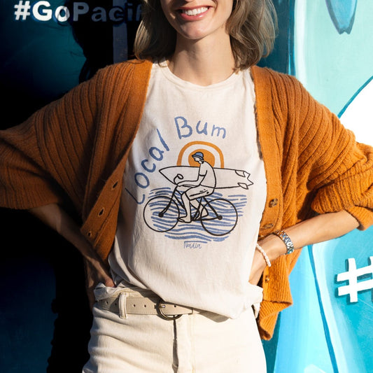 Local Bum Graphic Tee with illustrated character holding a surf board and riding a bicycle. Handmade t-shirt by artist Nadia Watts in Southern California