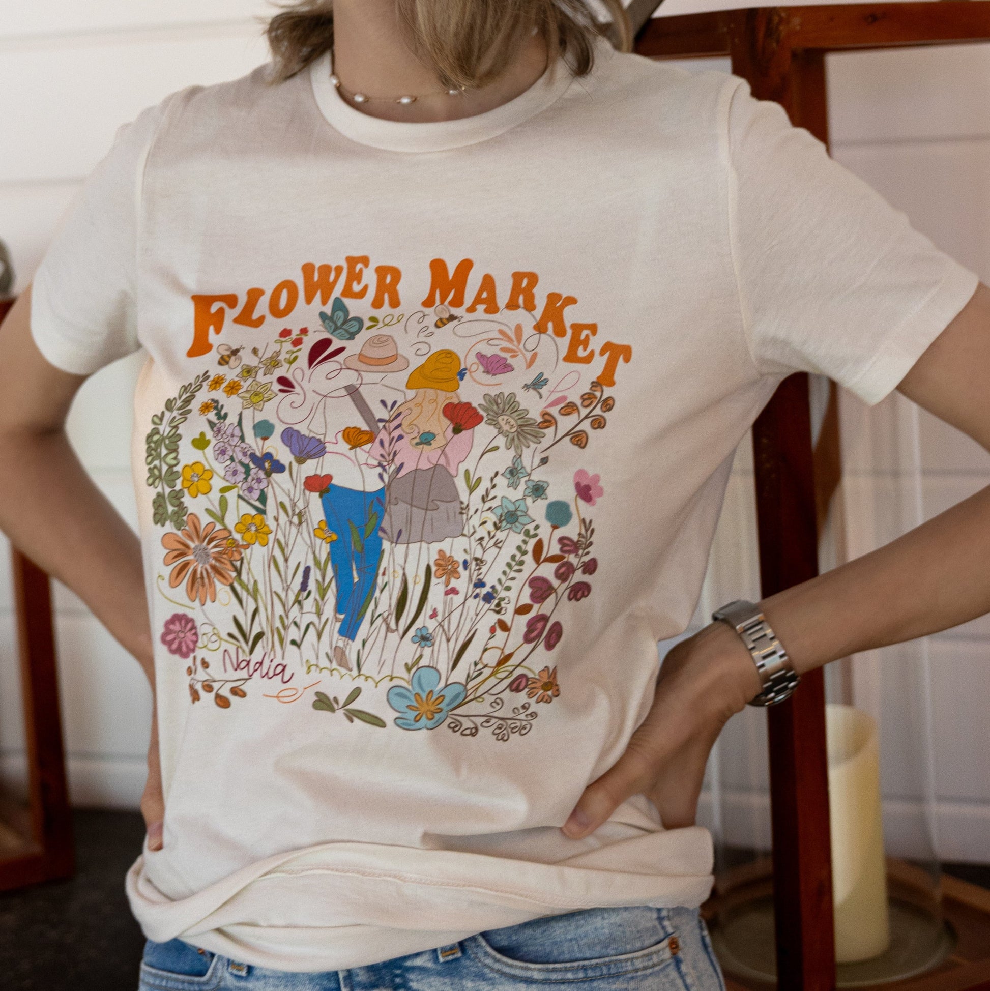 Floral graphic tee with colorful illustration of couple walking amidst flowers, Flower Market logo, women's off-white t-shirt