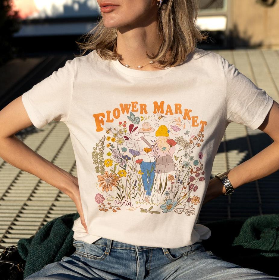 Floral graphic tee with colorful illustration of couple walking amidst flowers, Flower Market logo, women's off-white t-shirt