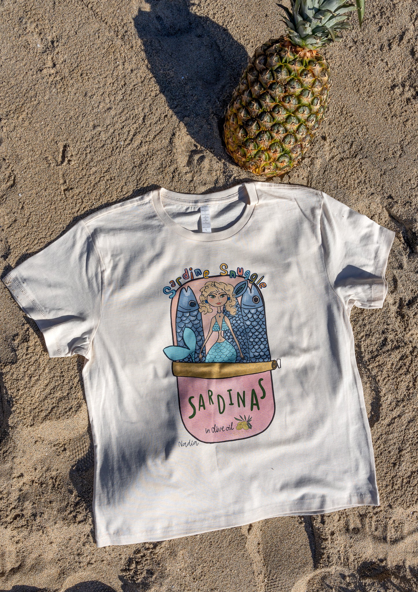 Unique mermaid graphic tee with hand-illustrated sardine can design.