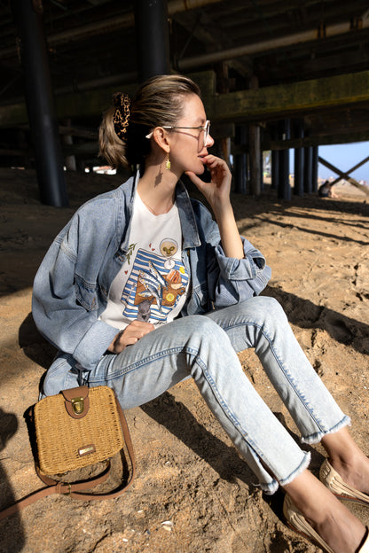 Sardinia illustrated tee showing hand‑drawn sardines, a dirty martini, bread, lemon, and a cat on an off‑white cotton shirt
