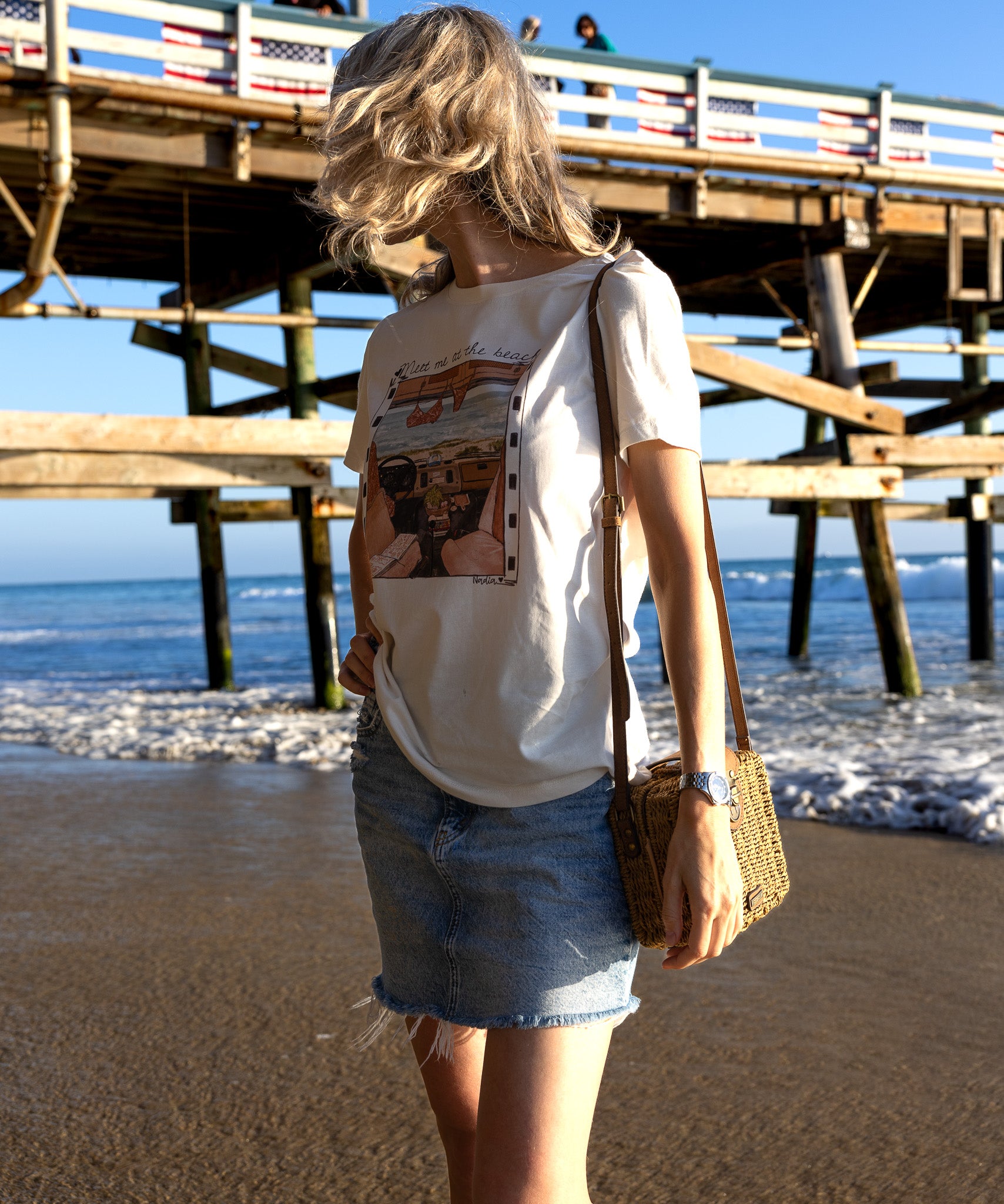 Woman standing on a beach with a pier in the background