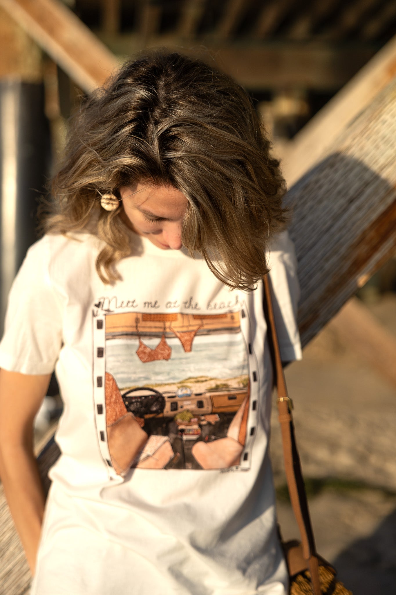 Woman wearing a white t-shirt with a graphic design, standing outdoors.