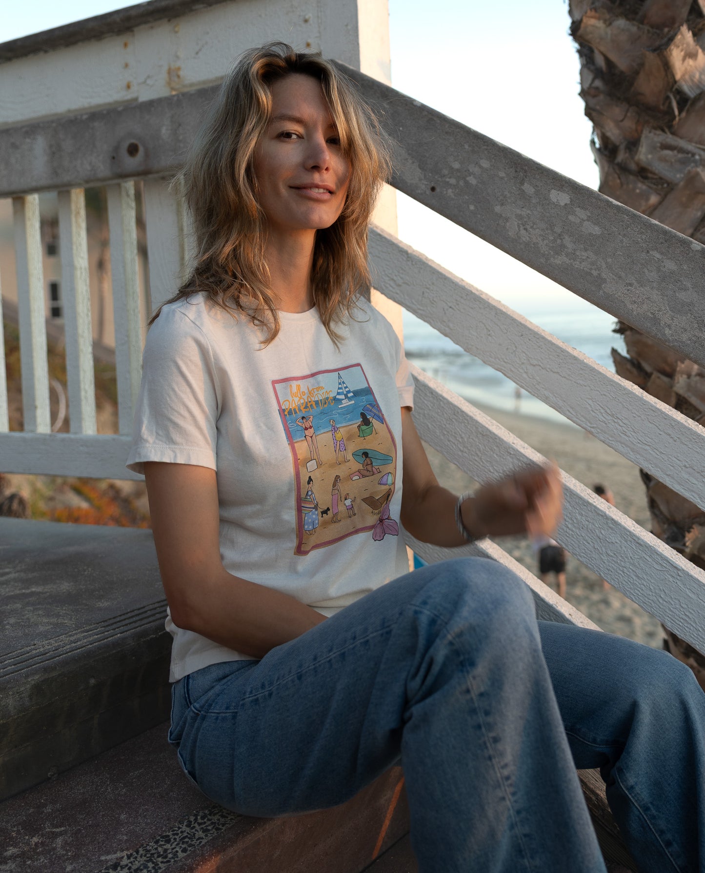 Women's soft cotton t-shirt with a hand-drawn "Hello from Paradise" tropical beach scene, North Shore Girls brand.