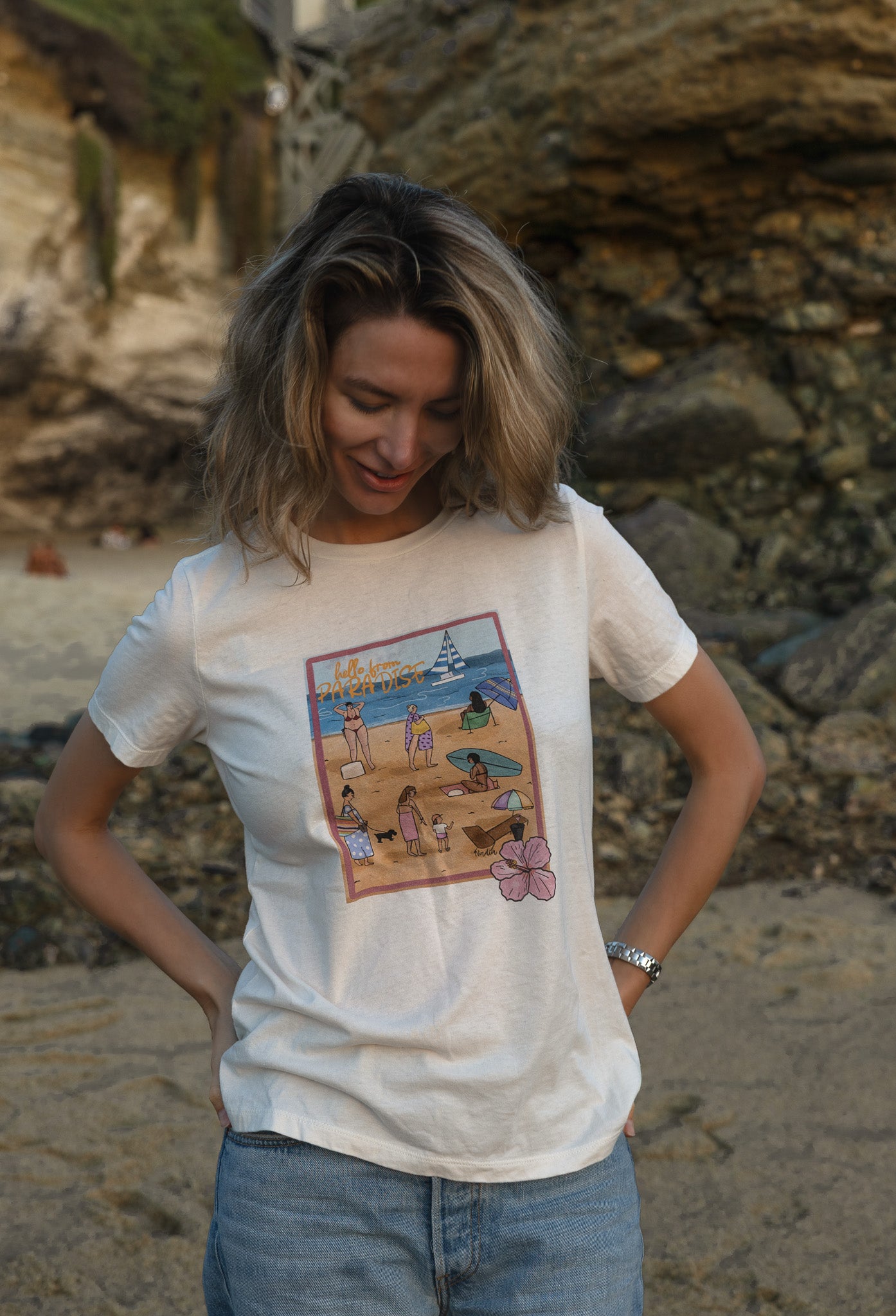 Women's soft cotton t-shirt with a hand-drawn "Hello from Paradise" tropical beach scene, North Shore Girls brand.