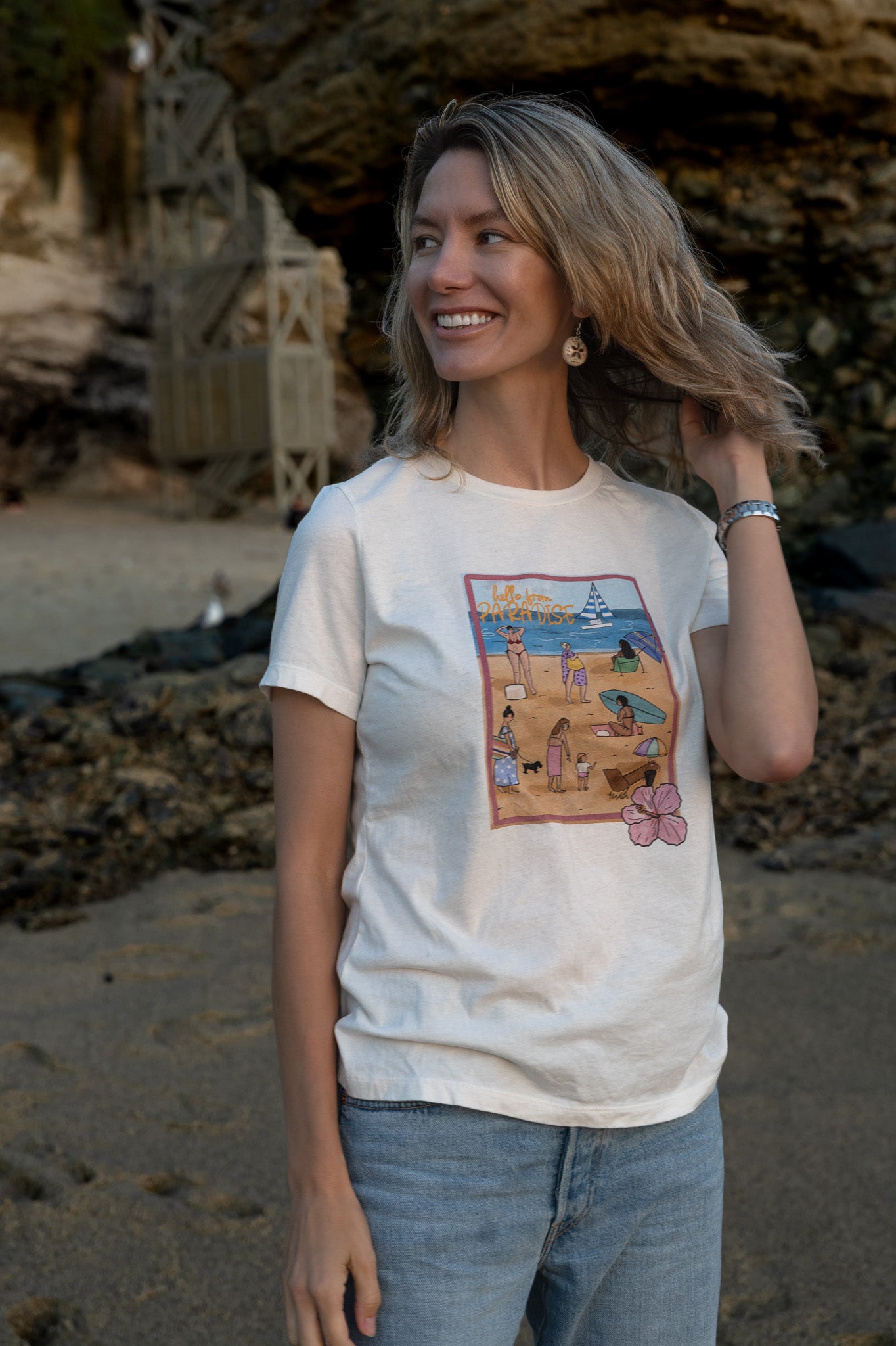 Women's soft cotton t-shirt with a hand-drawn "Hello from Paradise" tropical beach scene, North Shore Girls brand.