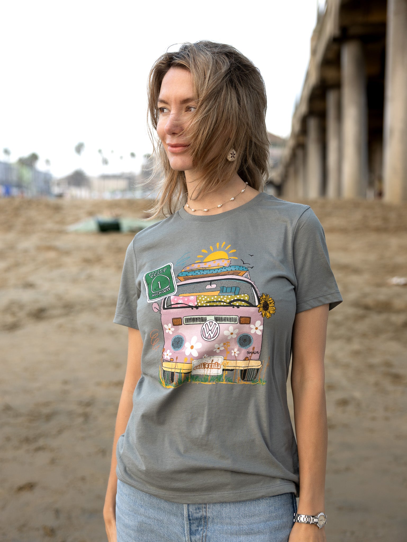 Woman in a grey North Shore Girls graphic t-shirt features a hand-drawn vintage floral beach van.