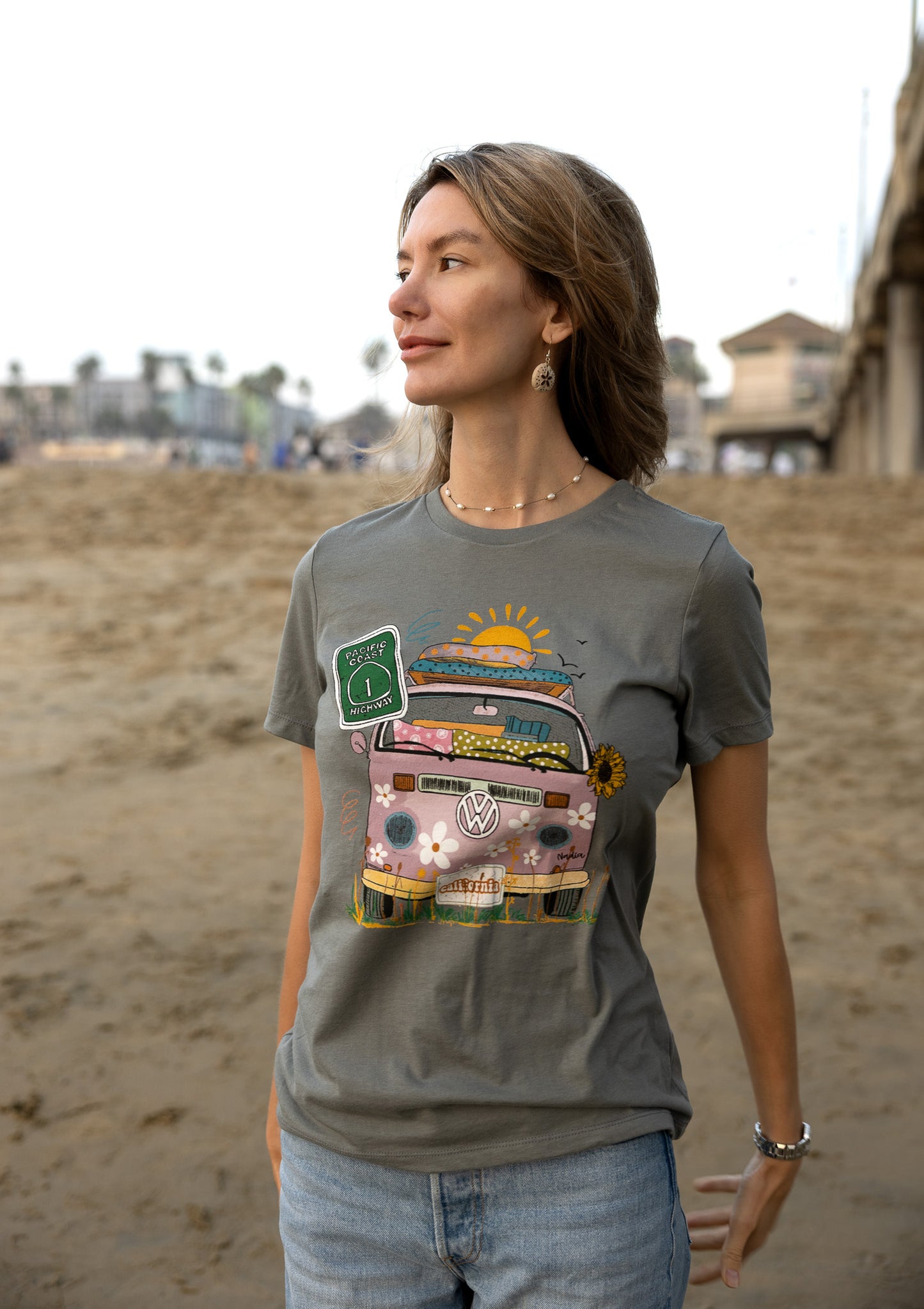Woman in a grey North Shore Girls graphic t-shirt features a hand-drawn vintage floral beach van.