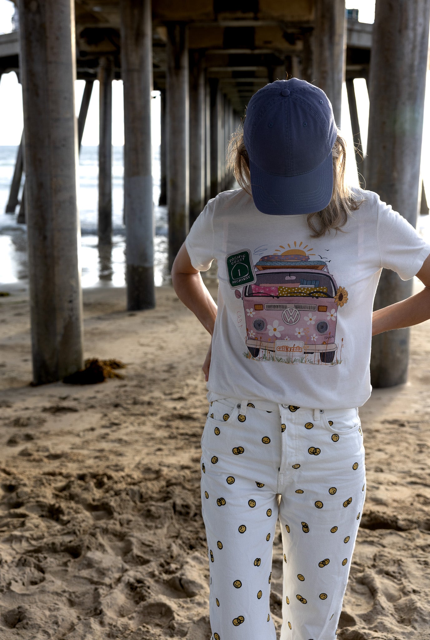 Pink VW bus graphic tee with floral details and “California” license plate, hand‑illustrated design on soft cotton