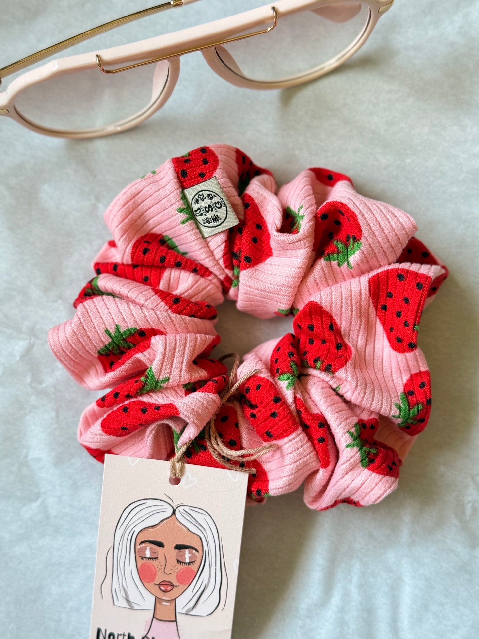 Hand-sewn ribbed scrunchie with a strawberry print and North Shore Girls woven label.