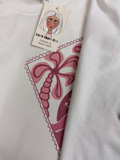 White t-shirt with pink graphic design and a tag featuring a stylized face.