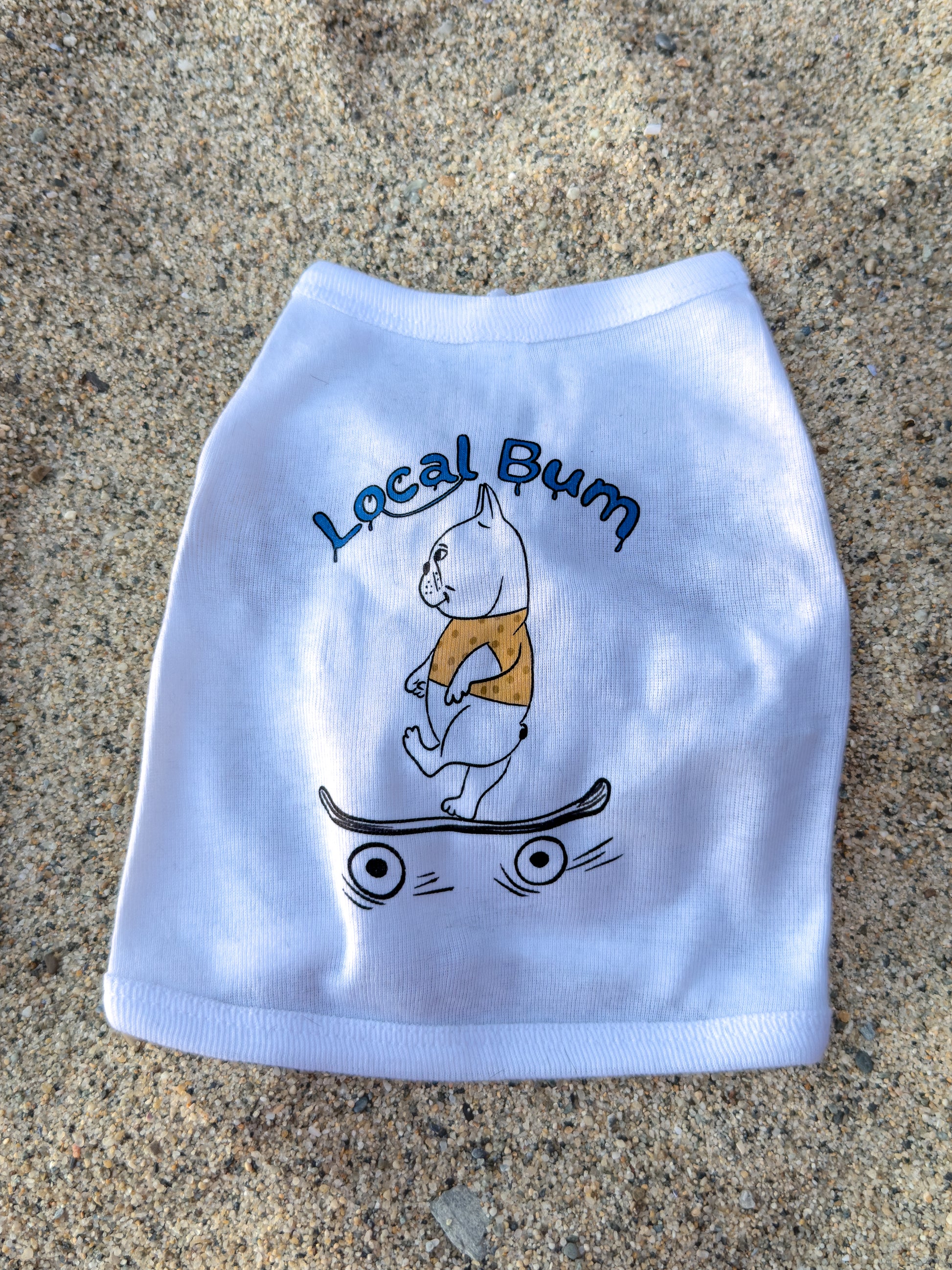 White pet shirt with a cartoon dog on a skateboard and 'Local Bum' text on a concrete surface.