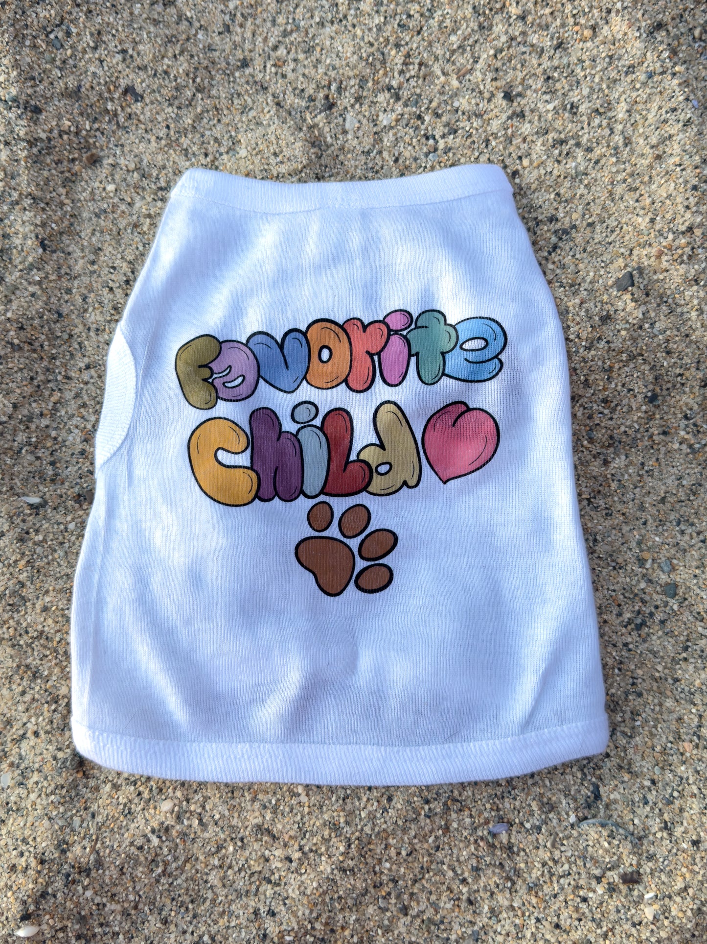White pet shirt with colorful text and paw print on a concrete surface