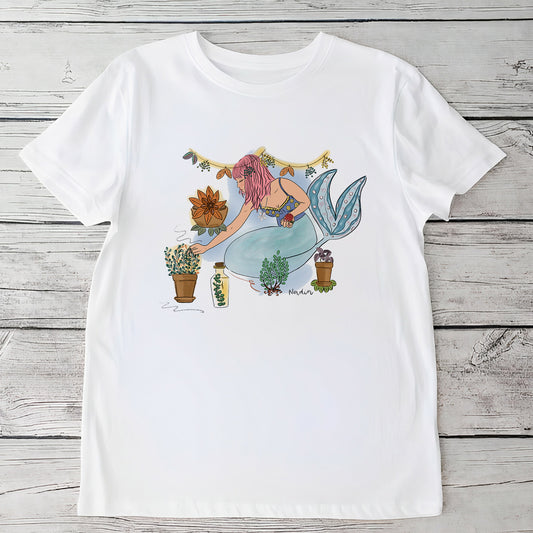 Youth white t-shirt with a hand-drawn mermaid tending to bohemian potted garden plants, North Shore Girls brand.