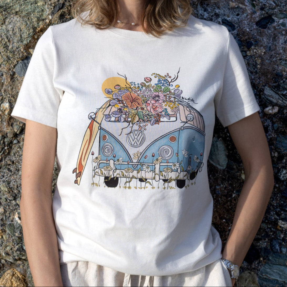 Woman wearing a North Shore Girls tee with an illustration of a blue van, surfboard, and flowers.