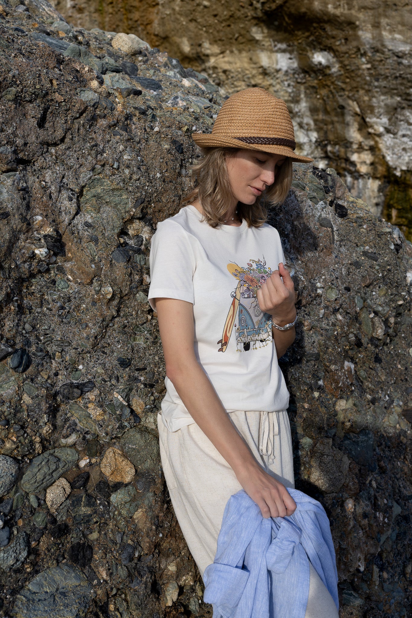 Woman wearing a North Shore Girls tee with an illustration of a blue van, surfboard, and flowers.