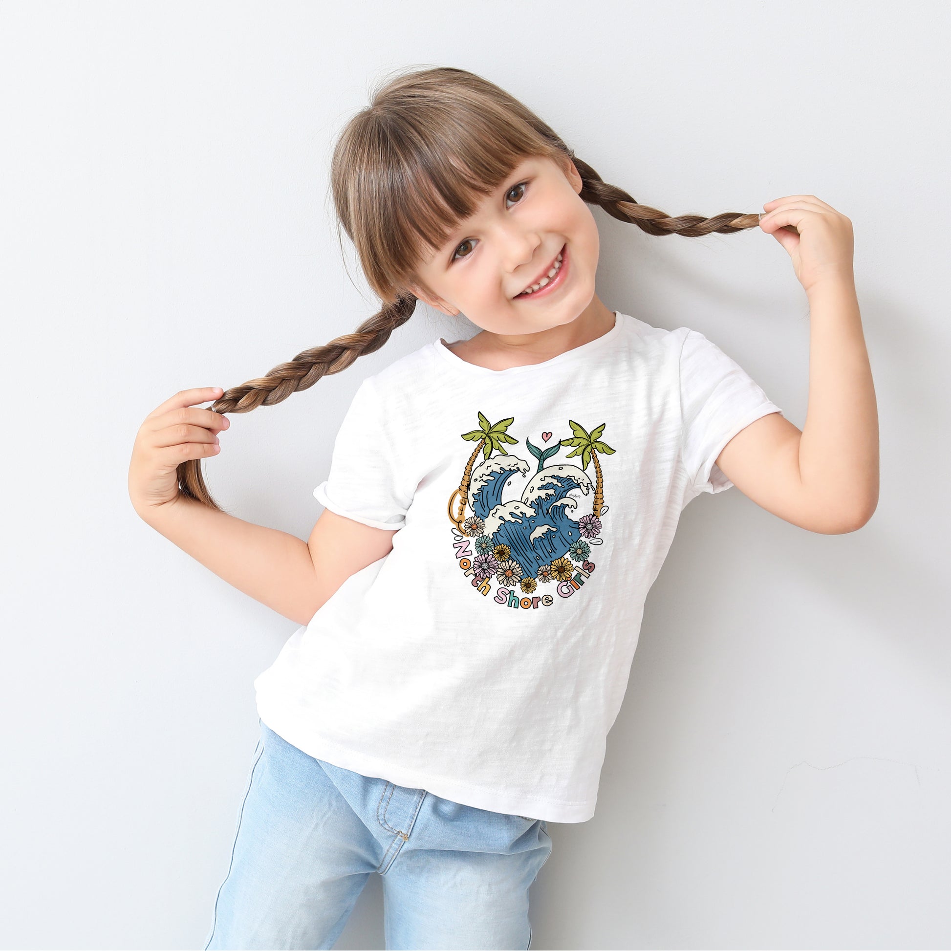 White toddler t-shirt featuring a hand-drawn ocean wave crest with palm trees and flowers, part of the North Shore Kids collection