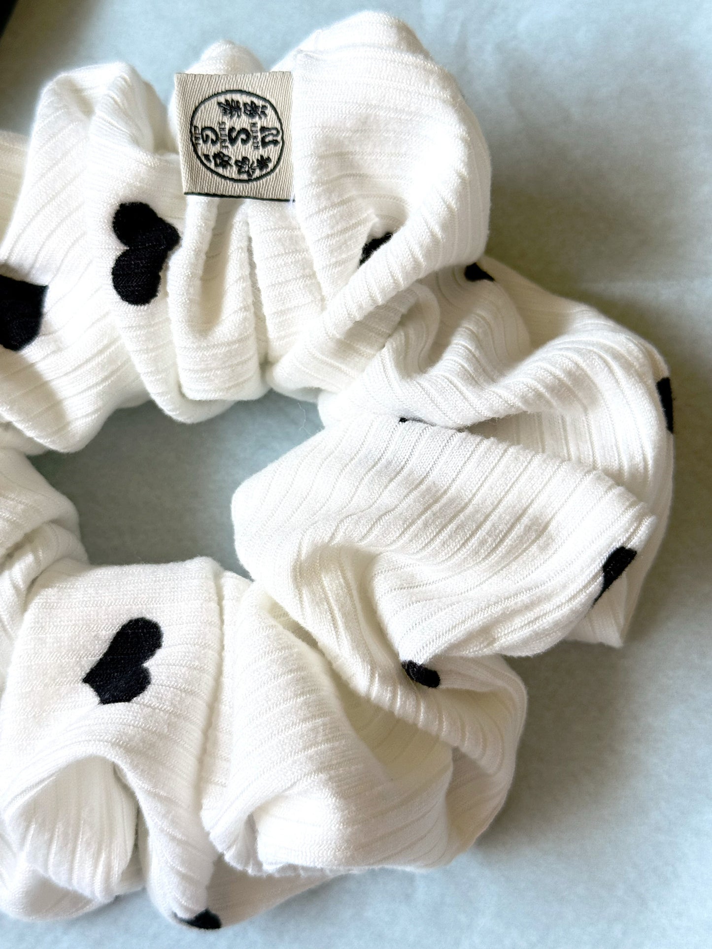 Hand-sewn ribbed scrunchie with a Black heart print and North Shore Girls woven label.