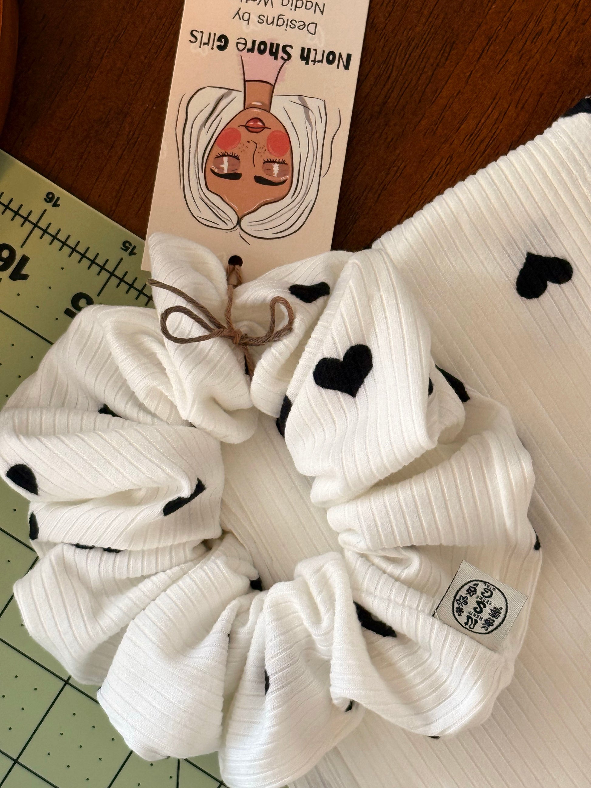 Hand-sewn ribbed scrunchie with a black heart print and North Shore Girls woven label.