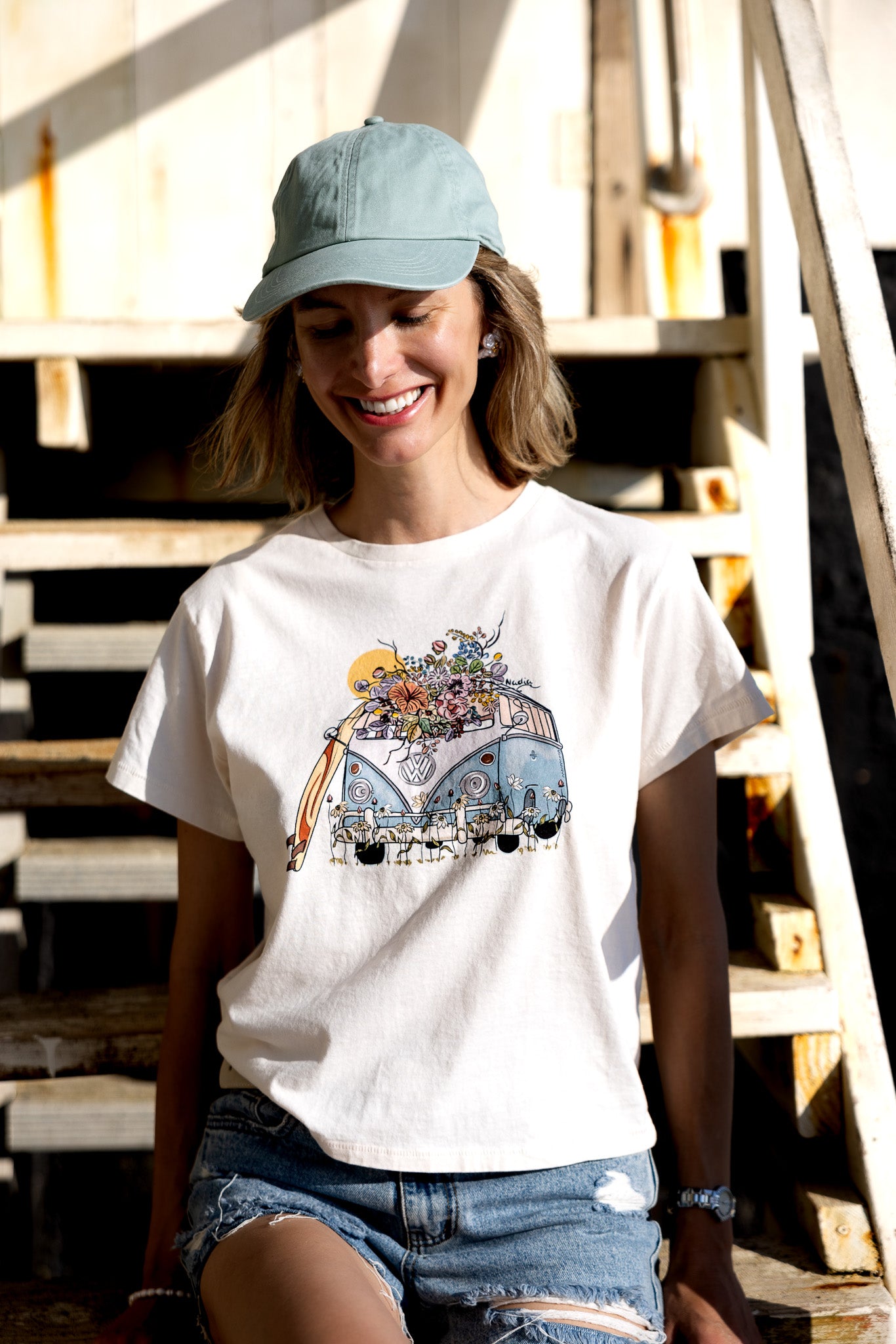 Hand-illustrated graphic tee featuring a colorful surf bus surrounded by floral details. The tee is a relaxed fit, made from 100% cotton, and includes the artist's signature.