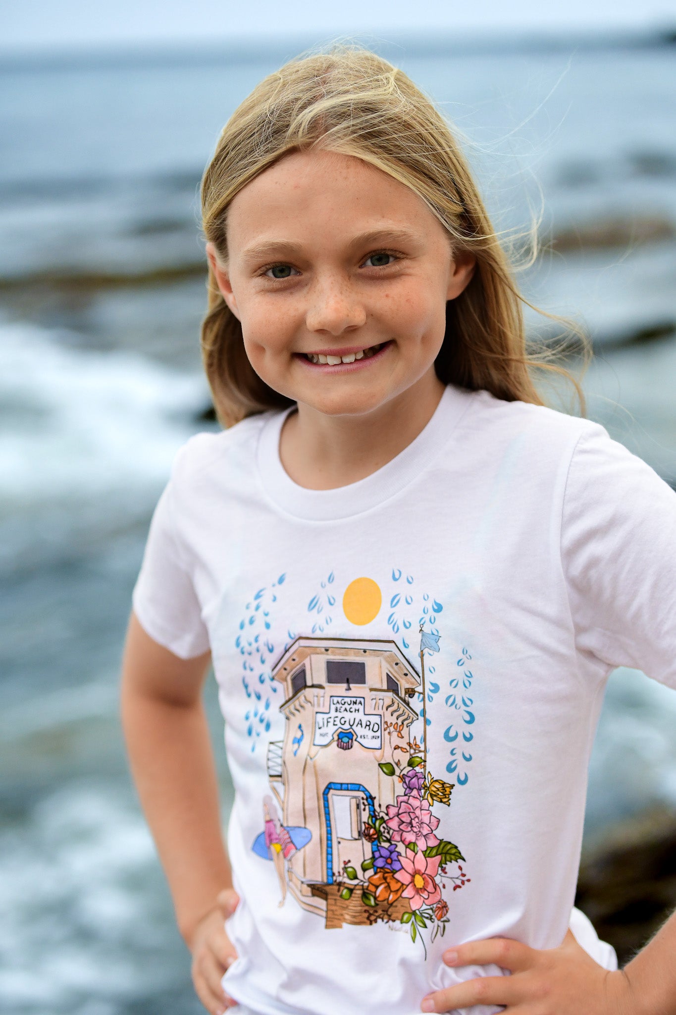 Load image into Gallery viewer, Laguna Beach Lifeguard Tower surfer girl and floral details illustrated graphic t-shirt for girls. 
