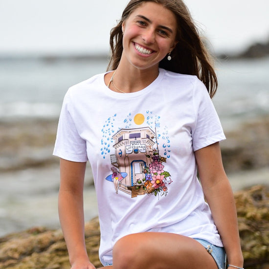 Laguna Beach Lifeguard Tower Surfer Girl Floral Illustrated graphic tee. Southern California beach town destination t-shirt. Artist designed graphic t-shirt for women