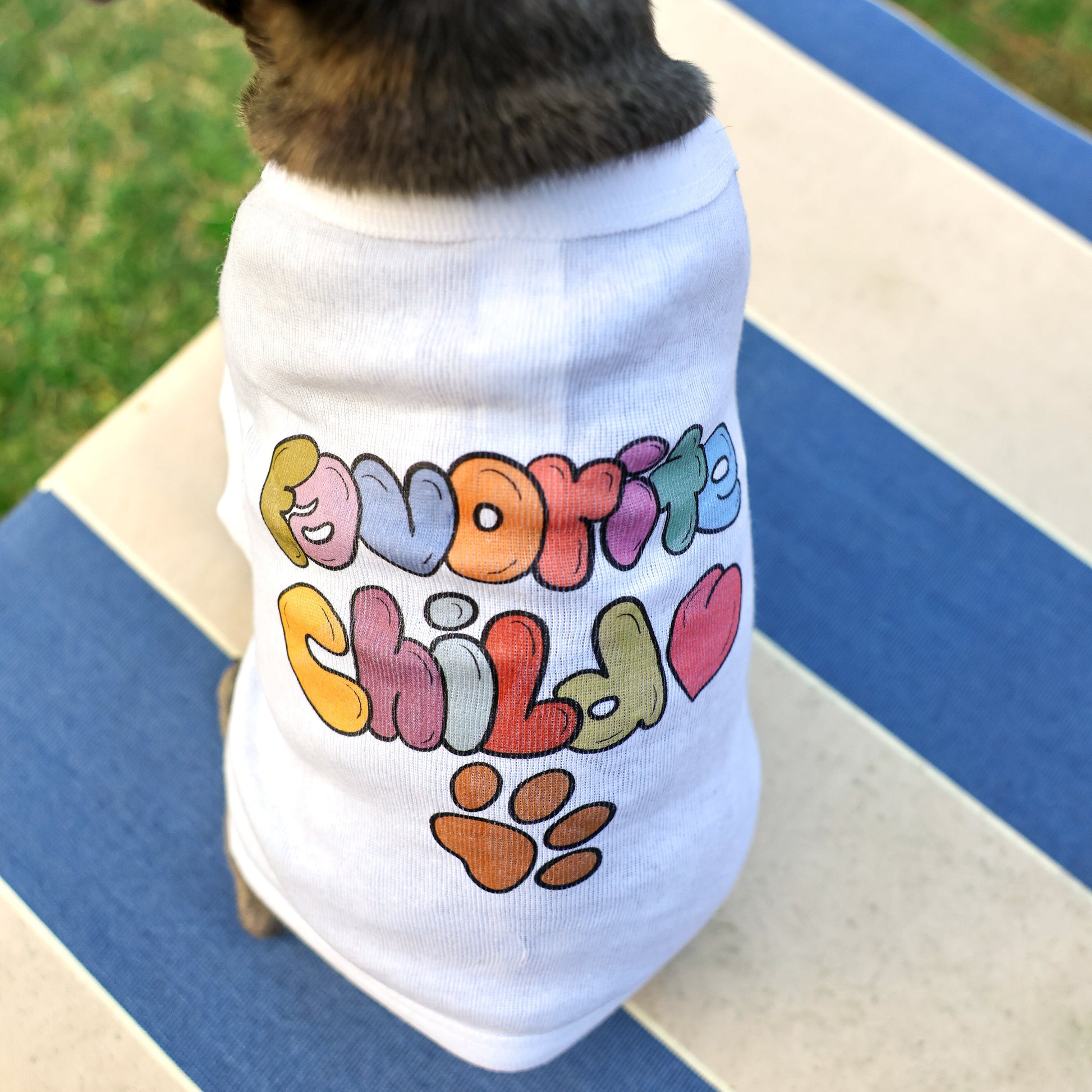 A French Bulldog wearing a white cotton tee with Favorite Child written in colorful hand-drawn letters.
