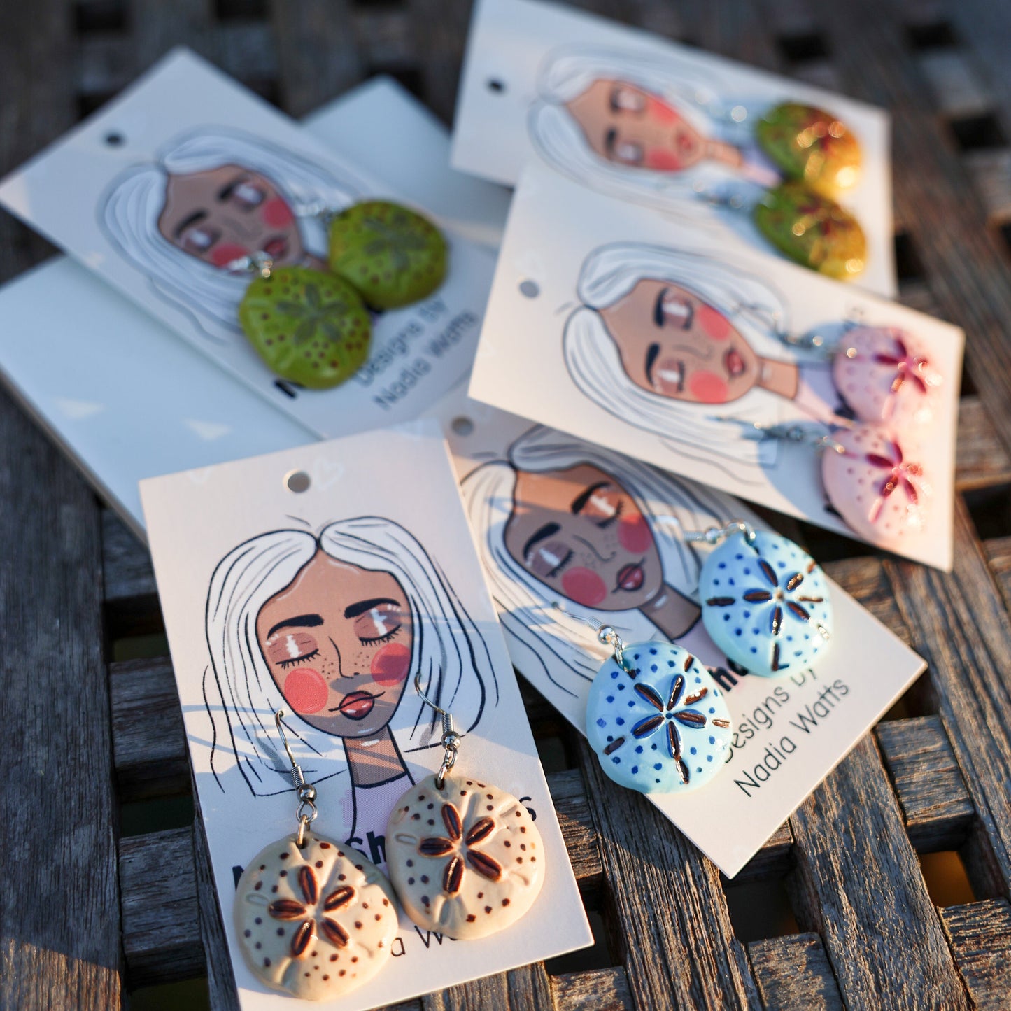 Hand-painted clay sand dollar earrings in coastal colors on signature illustrated cards