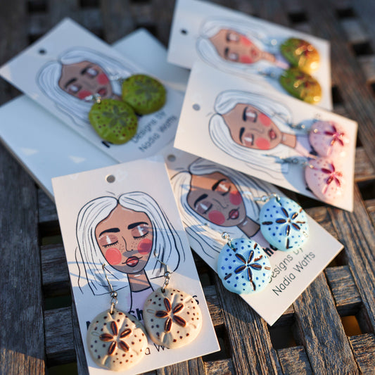 Hand-painted clay sand dollar earrings in coastal colors on signature illustrated cards