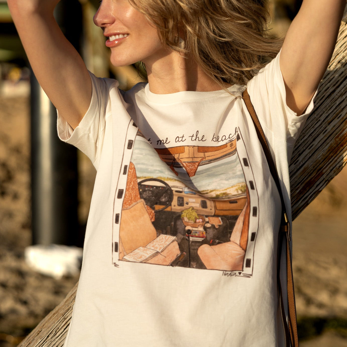 Women's cream-colored tee with a hand-drawn vintage car interior and Meet Me at the Beach text.