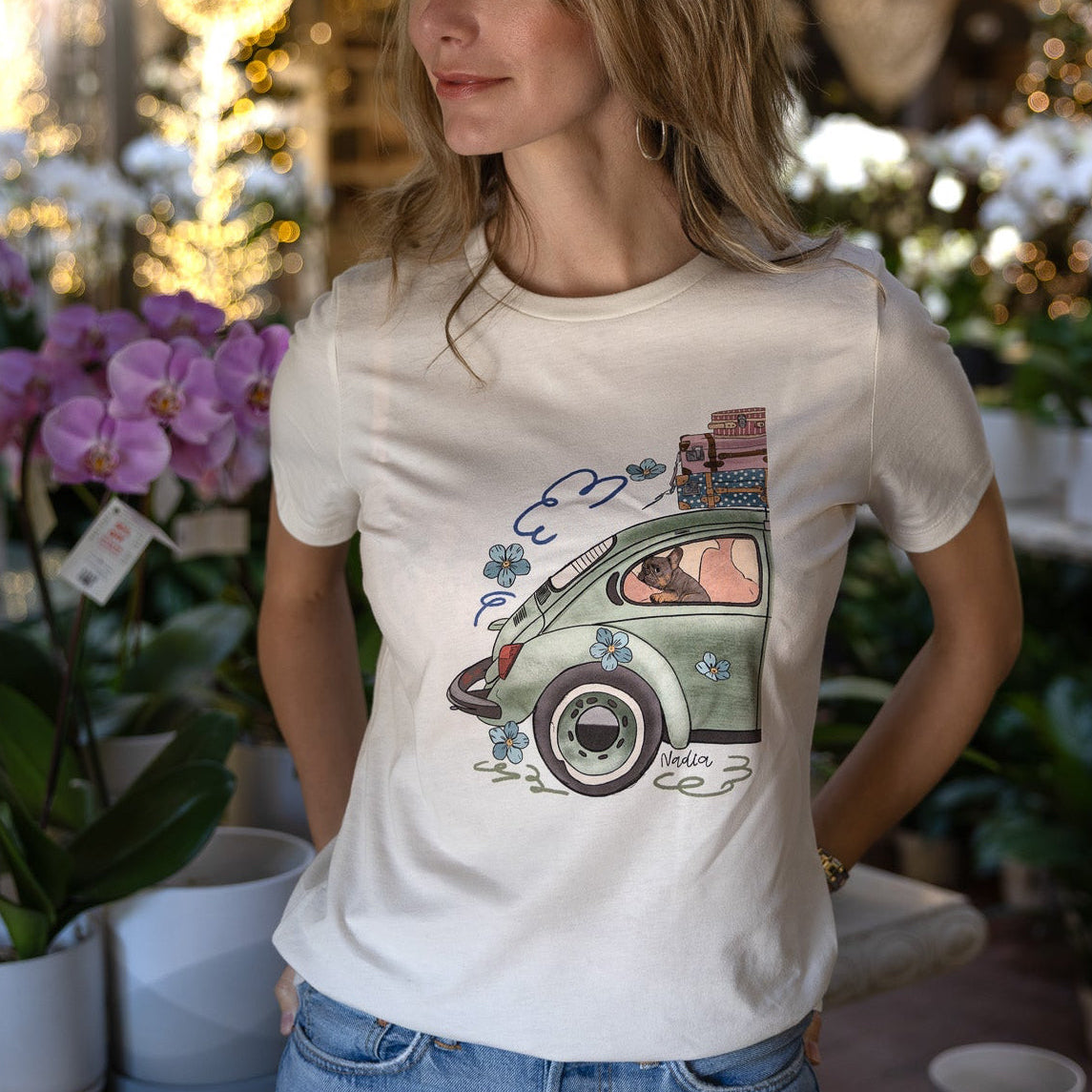Woman wearing a cream-colored North Shore Girls tee with an illustration of a green vintage car and a French Bulldog