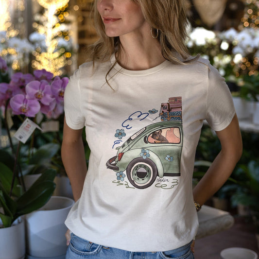Woman wearing a cream-colored North Shore Girls tee with an illustration of a green vintage car and a French Bulldog
