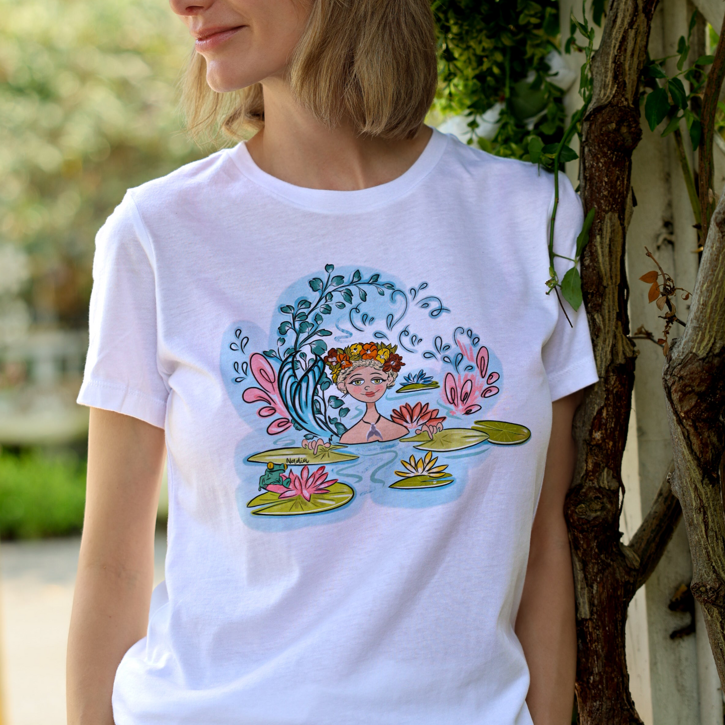 Hand-illustrated graphic tee featuring a mermaid surrounded by water lilies, printed on a relaxed fit women's t-shirt made from 100% cotton using high-quality technology. The graphic is intricately detailed and visually striking, making this tee a standout piece in any wardrobe.