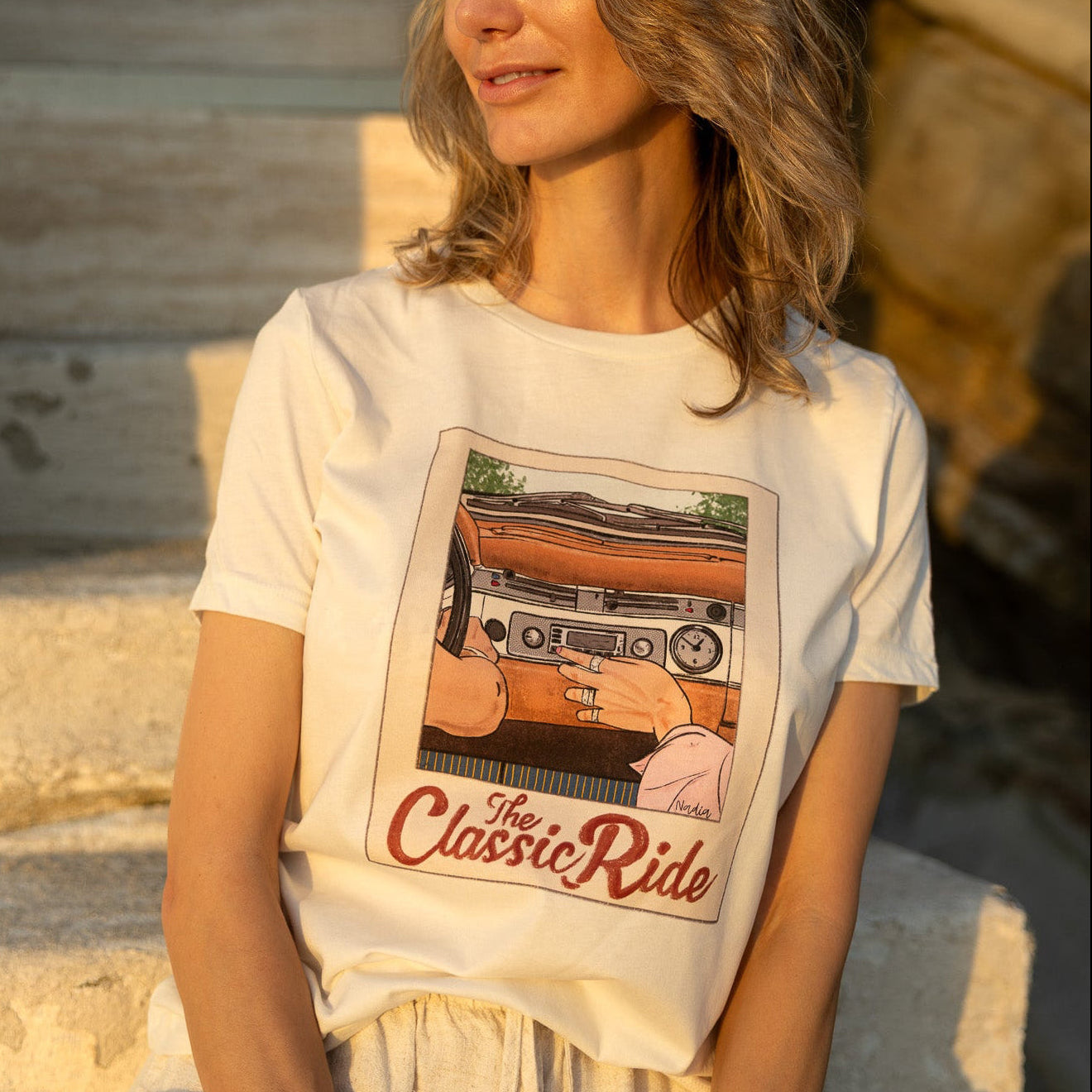 Close-up of a women's cream t-shirt featuring a hand-drawn vintage car dashboard and "The Classic Ride" text